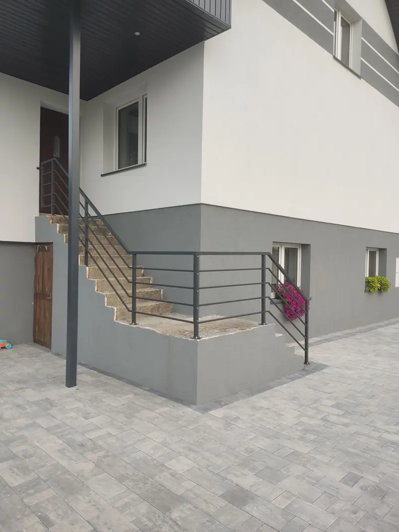 Balustrada z poziomych prętów stalowych przy schodach zewnętrznych domu