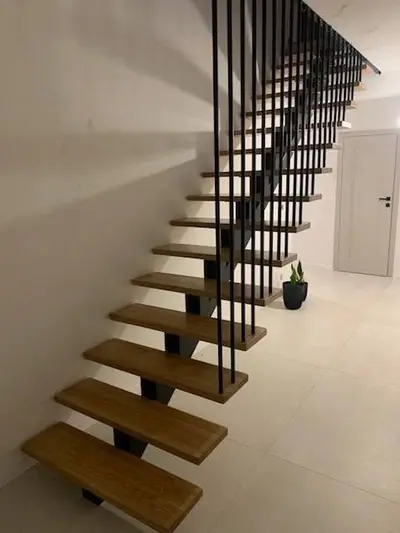 Schody wewnętrzne na stalowej konstrukcji z balustradą z pionowych prętów od schodów do sufitu